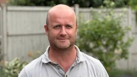 Alan Pickard Man smiling wearing a grey t shirt
