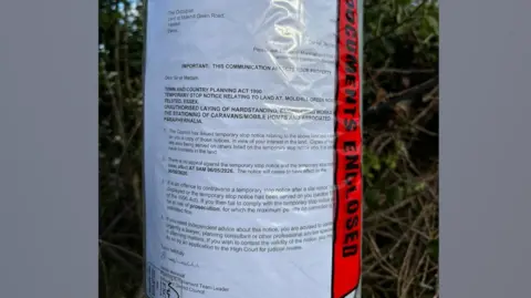 Supplied A Temporary Stop Notice, issued by Uttlesford District Council, attached to a telegraph pole. The notice is covered in transparent plastic.