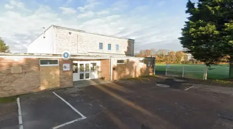 Picture shows the outside of the Wall's Social club, it's car park and a sports field