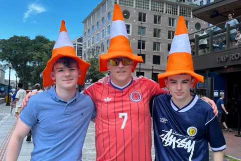 A man and his two sons either side of him - all three are wearing traffic cone hats