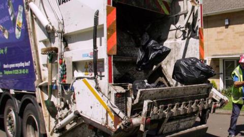 Waste bags are placed into a refuse lorry