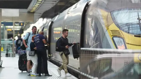 PA Passengers board a train at the Eurostar terminal at St Pancras station in central London. French rail officials say several lines have been hit by "malicious acts" which have heavily disrupted services ahead of the Olympics