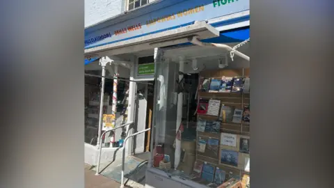 Oxfam Oxfam in Thame. It has large glass front windows with a doorway in the middle. Above the windows is a blue streak. Above the door is an Oxfam logo.