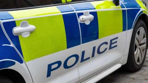 Close up of a United Kingdom police patrol response car with Battenberg markings.