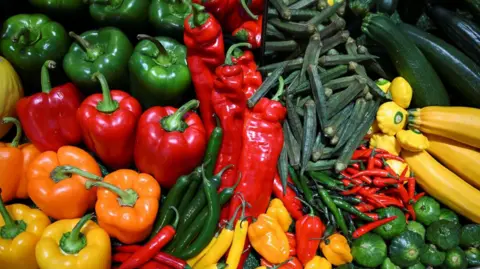 Reuters A variety of vegetables including peppers, chillies, squashes and courgettes. There are a variety of colours including green, red, orange and yellow.