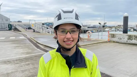 Ben Schofield/BBC Megan Dorsett standing on the quayside at the Port of Lowestoft 