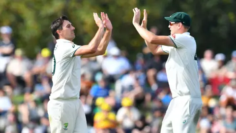 Australia's Pat Cummins (L) celebrates the wicket of New Zealand's Tim Southee with his teammate Cameron Green