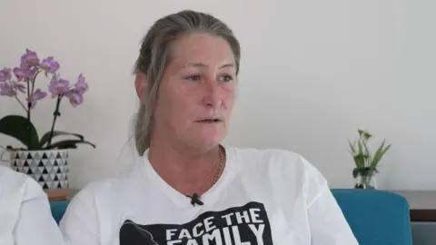 PA Media Cheryl Korbel with long blond hair wearing a black and white t-shirt during her campaign which read 'Face the family'. 