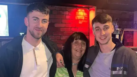 Family handout Debbie Slater (centre) with her sons Zak (left) and Jay