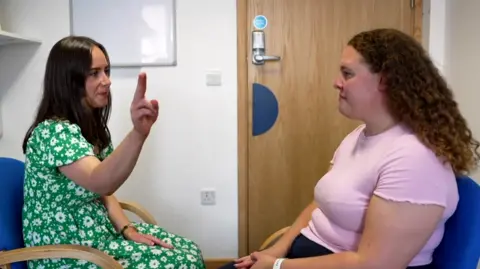 A therapist with her hand in the air in front of a patient demonstrating what Eye Movement Desensitisation and Reprocessing (EMDR) therapy is.