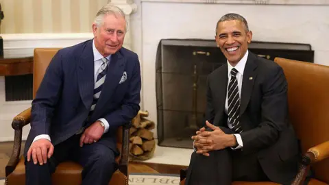 Getty Images Charles and Obama smiling for the camera as they sit in chairs at the White House