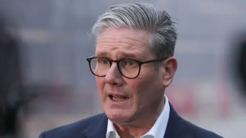 Getty Images Sir Keir Starmer, a man with grey hair and wearing black glasses and a blue blazer. He's talking to someone off camera.
