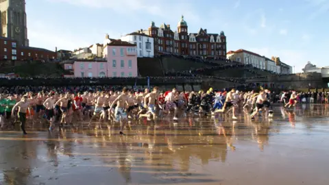 North Norfolk Beach Runners Hundreds of people dressed in swimwear run towards the sea on Cromer beach. 