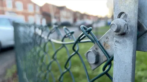 A fence on one of the military housing estates in Aldershot with army homes out of focus in the background.