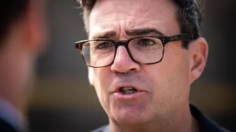 A close-up of Andy Burnham. He is wearing glasses. 