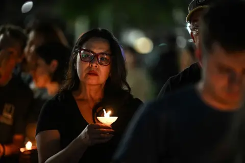 A woman holds a candle during a vigil for the victims of floods in Texas