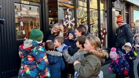 Michelle Flake A group of children stand by a barbershop waiting for sweets to be thrown.