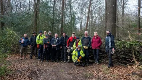 Surrey Choices and the team of volunteers at the Drove Road at Ranmore Common. They are all wearing outdoor clothing, with a number wearing high-viz clothing. 