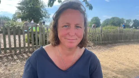 Richard Daniel/BBC Jessica Southwell has brown shoulder-length hair and is wearing a navy V-neck T-shirt.