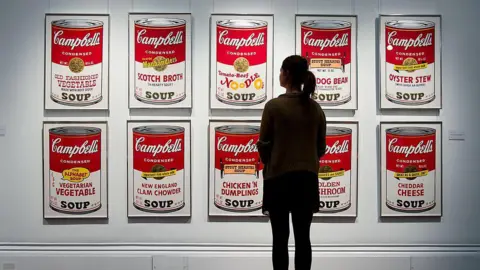 Getty Images Gallery assistant stands in front of Andy Warhol's iconic Campbell's Soup Can paintings.