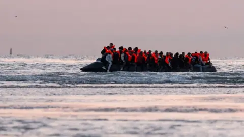  Migrants sit on a dinghy as it prepares to sail into the English Channel on July 10, 2025 in Gravelines, France.