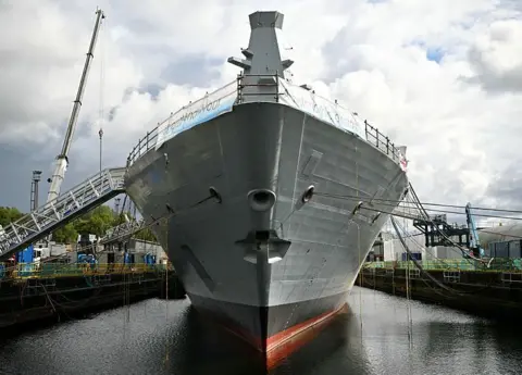 Getty Images A large ship, viewed bow on, in a fitting out dock