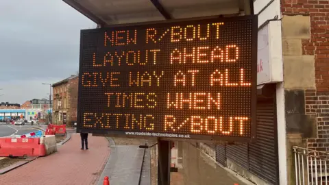 Simon Thake/BBC An electronic road sign with orange lettering