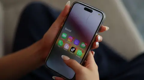 Reuters Close up of a person holding a mobile phone with social media apps displayed. 