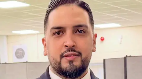 A man with short black hair and a short goatee beard. 