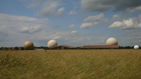 Bob Jones/Geograph Radar domes can be seen at an airfield with grass in the foreground