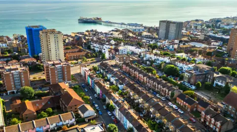 A view over homes and flats in Brighton. Brighton Pier and the sea is in the top of the image.