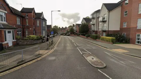 A Google street view image of a residential street. Terraced houses line both sides of the street. 