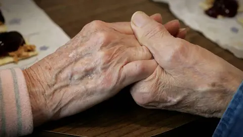 A close up of two hands holding together. One hand is older than the other.