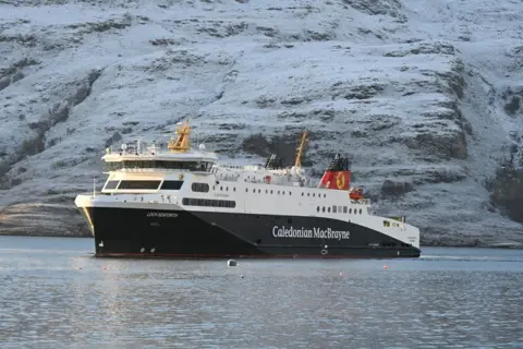 Craig Mailey A Caledonian MacBrayne ferry in traditional blue and white colours sails across a calm sea with a frosty hill in the background