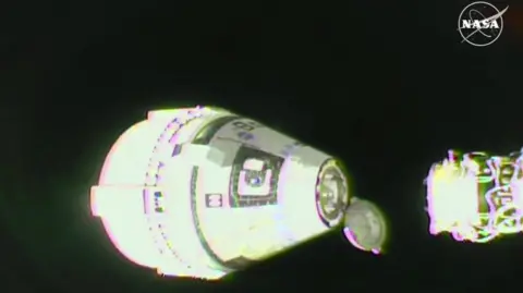 NASA The moment the capsule separates from the ISS and begins its journey to Earth. The capsule has a round bottom, narrowing into a cone shape. The part of the ISS that the capsule is attached to can also be seen in the image, with a large expanse of space visible in the background. 