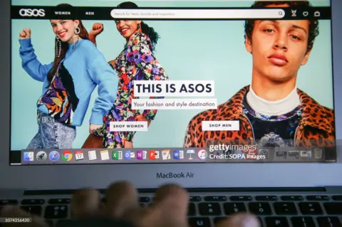 Getty Images La página de inicio de ASOS abierta en una computadora portátil con una mujer desplazándose