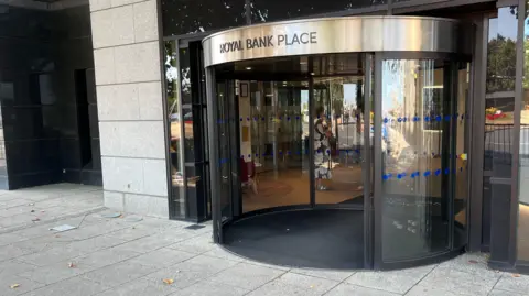 An automatic door that is ciurcular with the words Royal Bank Palace over the top of it. 