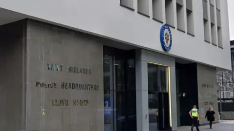 Google A large brick building with panels. The text on the wall reads West Midlands Police Headquarters Lloyd House. Police officers can be seen walking in front of the entrance.