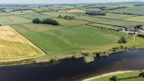 Destination Tweed An aerial shot looking down across green and yellow fields with a river in the foreground