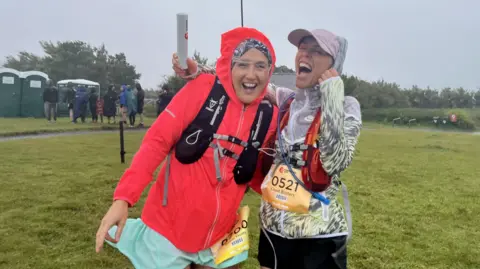 Two people wearing running gear, laughing before starting the race.