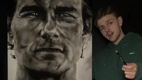 Wilf Elliott Tom Cruise drawn in charcoal on an A1 canvas whilst Wilf stands open-mouthed next to his work, holding a pencil.