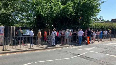 Alice Cunningham/BBC A group of parents gathered outside Sidegate Lane Primary School by a zebra crossing.