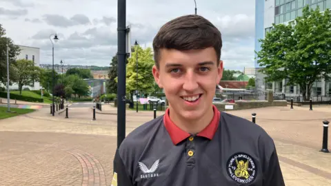 A young man outside a university campus.