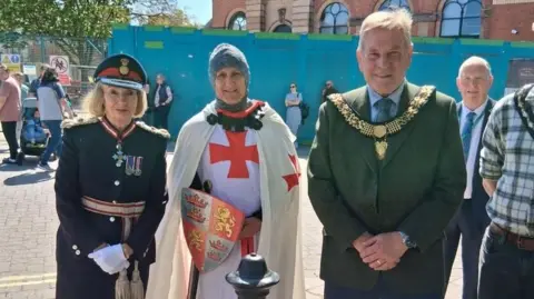 Alan Graves Three people stood together in union; left, woman in army attire, middle, man wearing tutor style fancy dress costume with a St George's cross, right, man in suit with mayoral gold sash