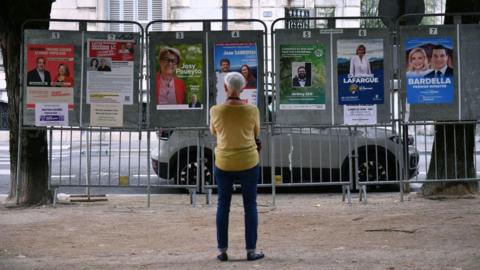 A woman looks at election posters