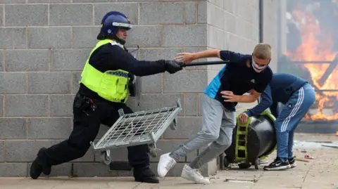 Reuters A police officer clashes with a protestor outside a hotel in Rotherham on 4 August