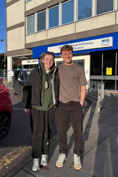 Katie Bain Katie and Ben are standing in front of the main entrance of Aberdeen Royal Infirmary after Katie's dischargement from the hospital. 