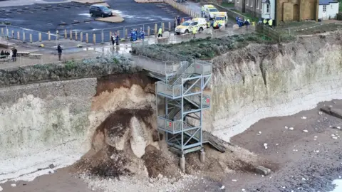 Eddie Mitchell Tonnes of chalk and dirt collapsed on the shingle and sand beach where a stairway is which leads from a car park to the beach 