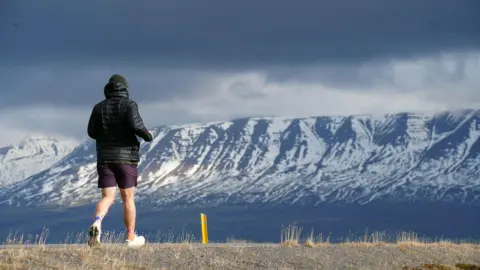  Robbie Guthrie/PA Seb Key running with his back to the camera. In front of him is an epic looking mountain range, with snow on it.