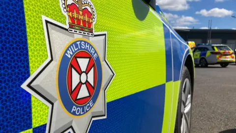 BBC Generic shot of the side of a Wiltshire police car - a close-up, showing the force logo.